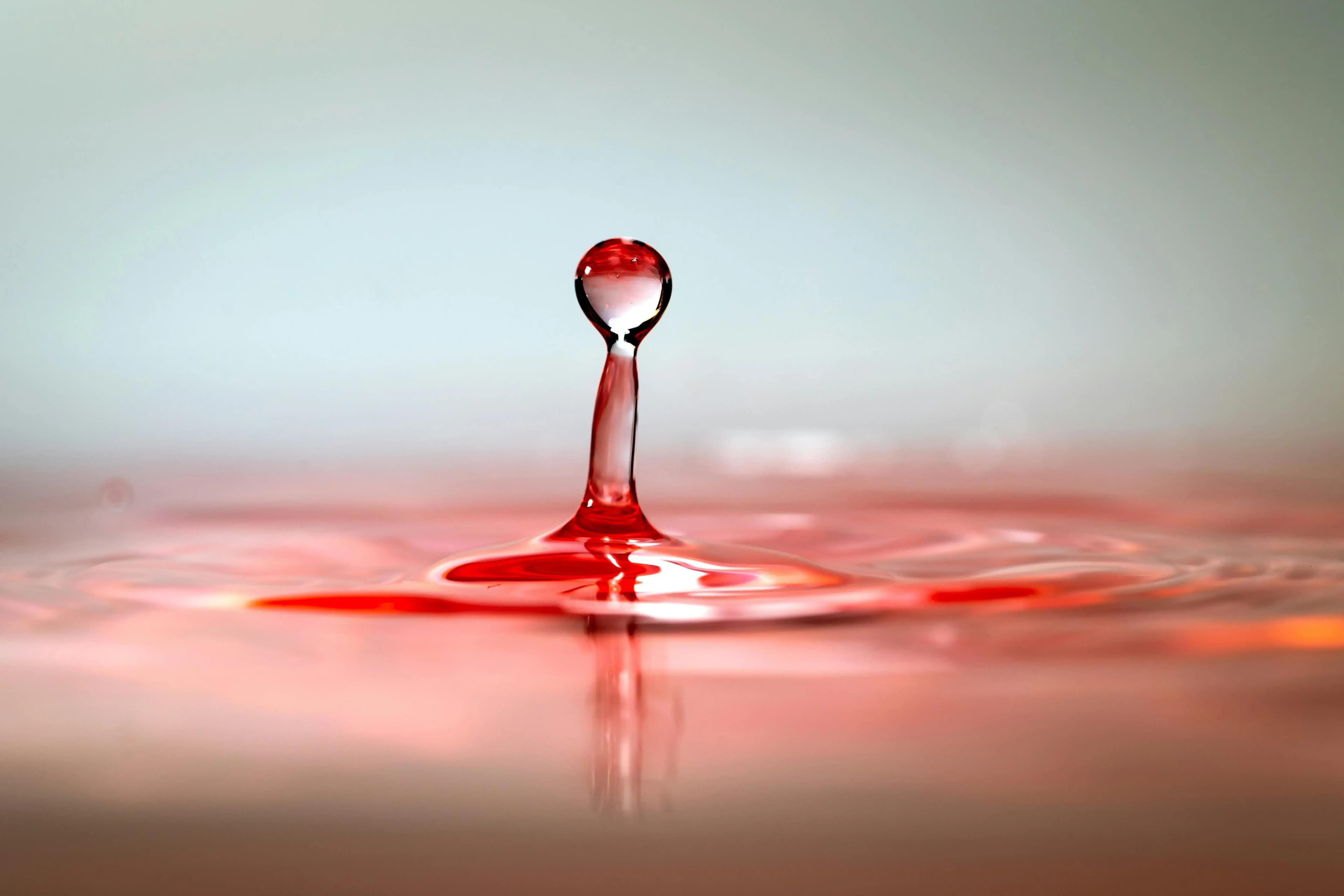 rosa Tropfen, der ins Wasser fällt