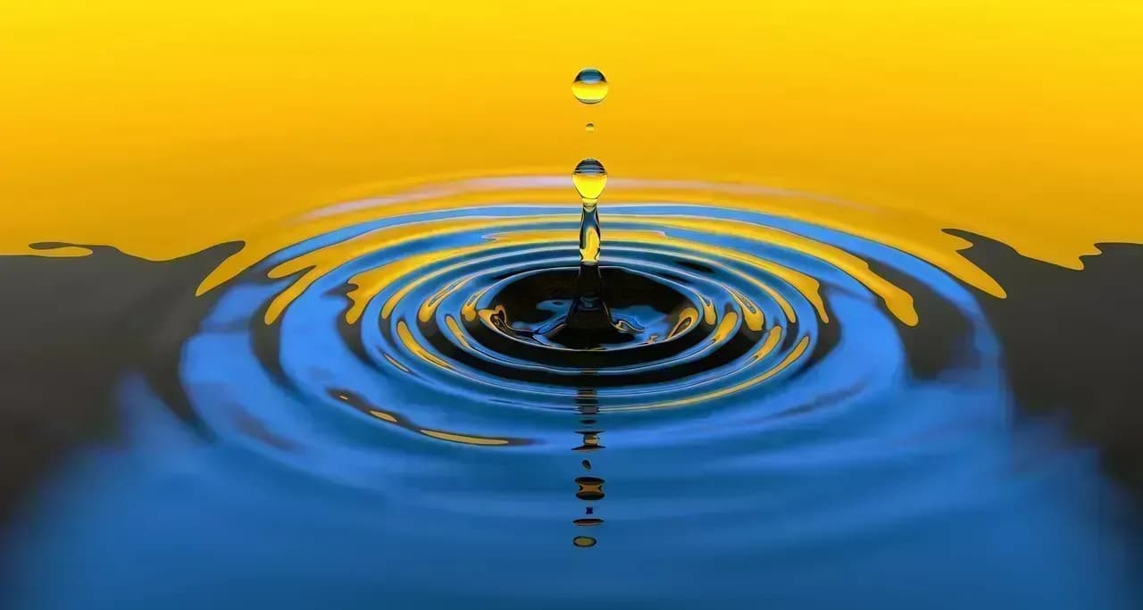 Tropfen der in blaues Wasser fällt