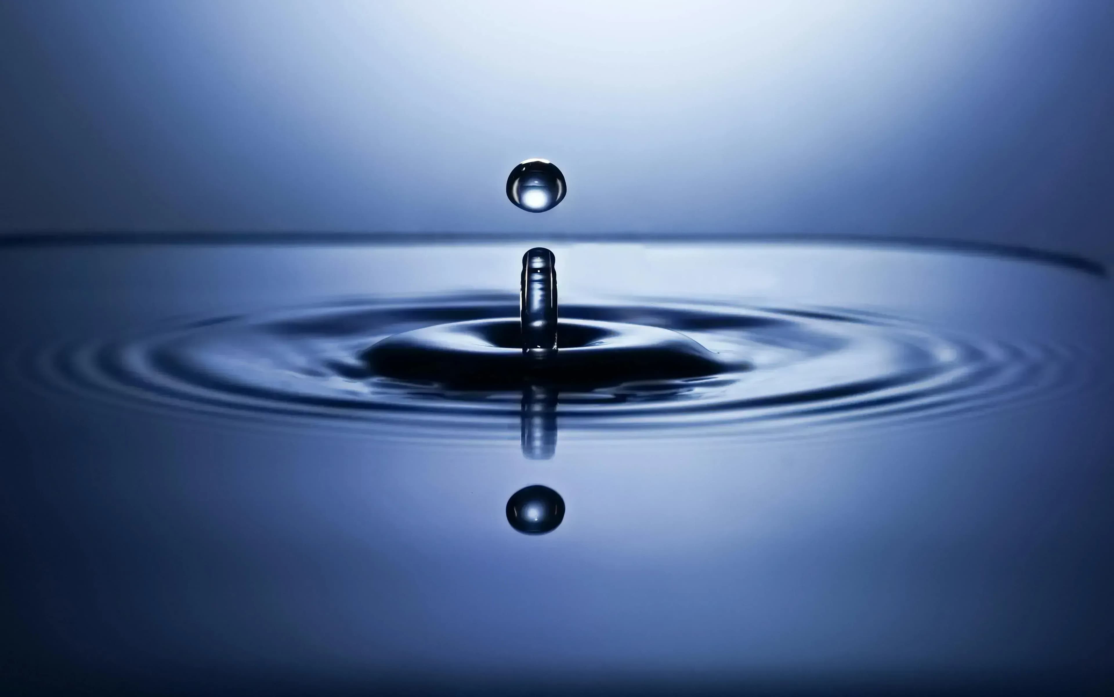 Tropfen der in blaues Wasser fällt