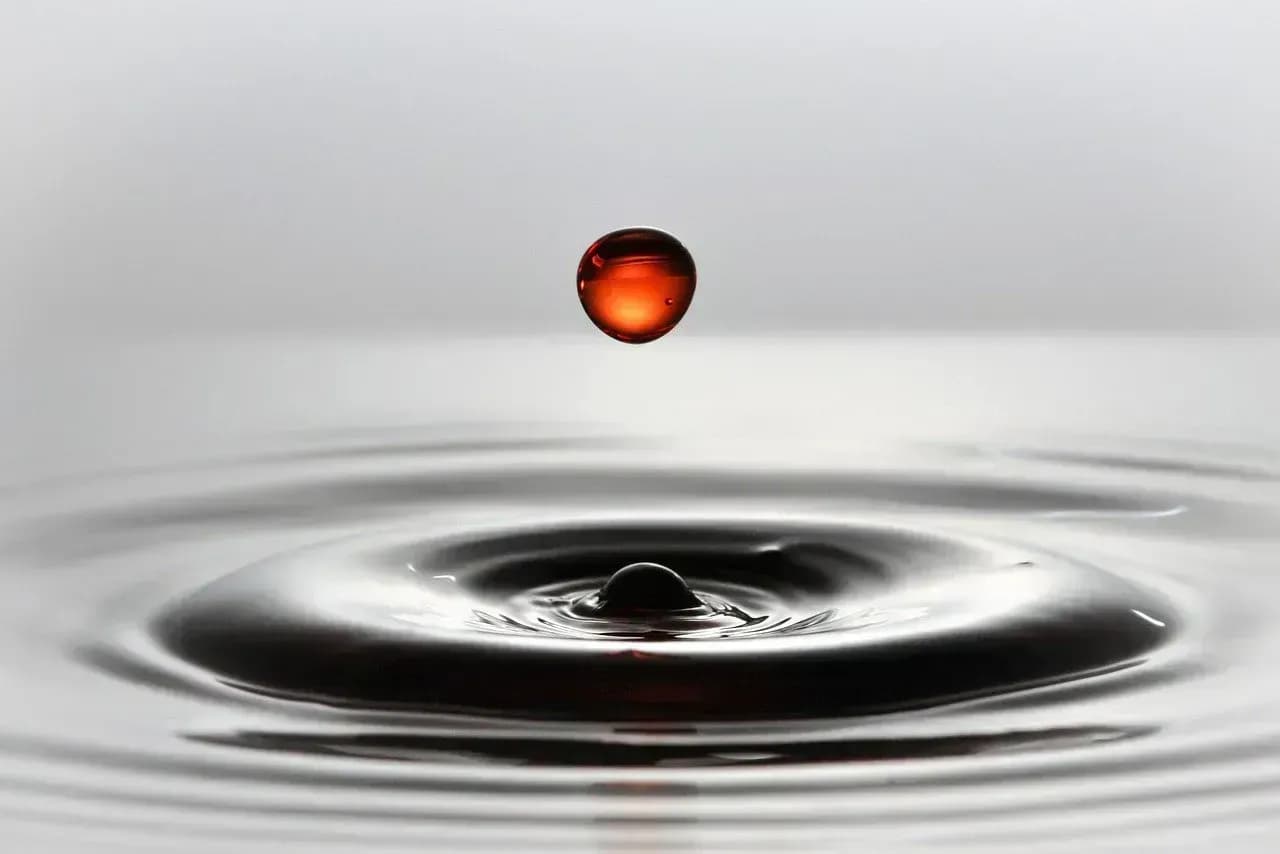 oranger tropfen, der in Wasser fällt